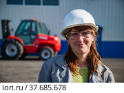 Portrait of young caucasian attractive engineer woman in white hardhat and protective glasses. Red hoist blurred on background (2012 год). Редакционное фото, фотограф Alexey Rezvykh / Фотобанк Лори