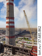 Aerial view of GRES-1 steam power station.Demolition of old raw coal bunkers.Yellow crane, smoke stack.Coal harvesters, dust and conveyor on background.Blue sky.Ekibastuz, Pavlodar reg., Kazakhstan. Стоковое фото, фотограф Alexey Rezvykh / Фотобанк Лори