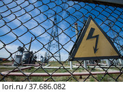 Electric transformer and distribution substation. Hand-made sign of high voltage on fence. Blue sky background. Стоковое фото, фотограф Alexey Rezvykh / Фотобанк Лори