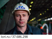 Aksu, Pavlodar region, Kazakhstan - May 29, 2012: Aksu steam power station. Portrait of serous adult caucasian worker in white hardhat. Close up photo. Blurred background. Редакционное фото, фотограф Alexey Rezvykh / Фотобанк Лори