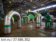 Aksu, Pavlodar region, Kazakhstan - May 29, 2012: Aksu steam power station workshop. Pipes with thermal insulation and shiny metal cover. Green electric machine, steam turbine and generator. Редакционное фото, фотограф Alexey Rezvykh / Фотобанк Лори