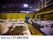 Temirtau, Kazakhstan - June 09, 2012: Concrete sleepers manufacturing plant NORD Prom NS. Young worker woman in white hardhat and the pouring machine. Редакционное фото, фотограф Alexey Rezvykh / Фотобанк Лори