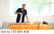 Positive male osteopath treating legs of woman patient. Стоковое видео, видеограф Гурьянов Андрей / Фотобанк Лори