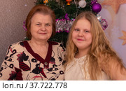 Радостные бабушка и внучка около новогодней елки в новогодние праздники. Стоковое фото, фотограф Мария / Фотобанк Лори