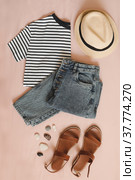 flat lay composition with female top, denim shorts, sandals and a wicker rattan bag on beige background top view. Стоковое фото, фотограф Galina kondratenko / Фотобанк Лори