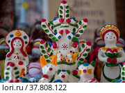 Крупным планом игрушка Дерево жизни (в центре) хлудневской глиняной игрушки лежит на прилавке на фестивале "Тула - мастерская России" в городе Туле, Россия (2022 год). Редакционное фото, фотограф Николай Винокуров / Фотобанк Лори