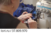Elderly woman sewing navy blue dress using sewing machine. Стоковое видео, видеограф Константин Шишкин / Фотобанк Лори