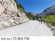Group of tourists walk along a mountain road on a sunny day. Travel, walks in nature and hiking in the mountains. The concept of active recreation. Nuhu pass, Mondy-Orlik road, Buryatia. Стоковое фото, фотограф Виктория Катьянова / Фотобанк Лори