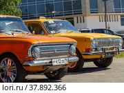 Old Soviet car Moskvich-408 and GAZ-24. Yellow car of Volga brand as a taxi (2020 год). Редакционное фото, фотограф Евгений Ткачёв / Фотобанк Лори