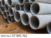 Concrete pipes to replace the city sewer system are lying on the sand and ready for installation. Стоковое фото, фотограф Юрий Пилия / Фотобанк Лори