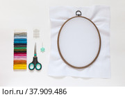 Needlework and embroidery. Accessories: needles, set of colored mouline threads, needle threader, scissors and cotton canvas on the oval  hoop for stitch or cross-stitch embroidery. Copy space, flat lay. Стоковое фото, фотограф Виктория Катьянова / Фотобанк Лори