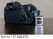 CFexpress memory card next to the camera on the table. Стоковое фото, фотограф Хилько Алексей / Фотобанк Лори