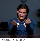 Young convict man sitting in dark room. Стоковое фото, фотограф Elnur / Фотобанк Лори