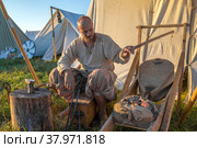 Кузнец-оружейник раздувает горн походной кузницы. Исторический лагерь фестиваля "Былинный Берег - 2022". Тверская область. Редакционное фото, фотограф Виктор Карасев / Фотобанк Лори