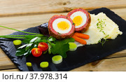 Dish scotch egg with tomatoes, mashed potatoes and greens, traditional Scottish cuisine. Стоковое фото, фотограф Яков Филимонов / Фотобанк Лори
