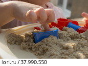 The child develops hand motor skills using kinetic sand. Стоковое фото, фотограф Екатерина Малиева / Фотобанк Лори