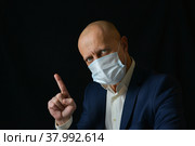 Мужчина в медицинской маске указывает пальцем вверх, свободное место для текста. Стоковое фото, фотограф Виталий Михайлюк / Фотобанк Лори