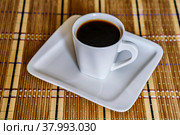 Чёрный кофе в белой чашке на салфетке-циновке на столе крупным планом. Стоковое фото, фотограф Владимир Устенко / Фотобанк Лори