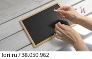 Women's hands take chalk over a children's blackboard on the table. Стоковое видео, видеограф Катерина Белякина / Фотобанк Лори