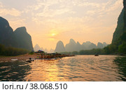 China. Yangshuo. Xingping. Beautiful Li (Lijiang) River with green karst hills at sunset. Tourists travel along the river on traditional bamboo rafts and admire the setting sun in an unusual natural park (2011 год). Стоковое фото, фотограф Виктория Катьянова / Фотобанк Лори