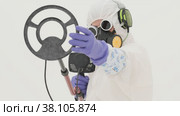 Man in white chemical protection suit holds metal detector. Стоковое видео, видеограф Aleksey Kidisyuk / Фотобанк Лори