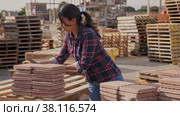 Female worker in gloves sorting red paving slabs in warehouse of building materials. Стоковое видео, видеограф Яков Филимонов / Фотобанк Лори