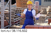 Attractive young female worker checking quantity of bricks in warehouse of building materials. Стоковое видео, видеограф Яков Филимонов / Фотобанк Лори