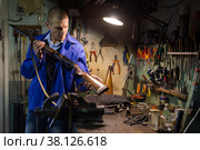 Gunsmith examines an automatic rifle before being repaired in weapons workshop. Стоковое фото, фотограф Яков Филимонов / Фотобанк Лори