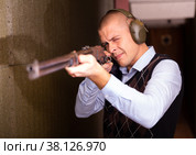 Confident shooter sighting in or zeroing shotgun in shooting gallery. Стоковое фото, фотограф Яков Филимонов / Фотобанк Лори