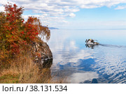 Baikal Lake in September. Red rowan trees on shore of Cape Shamansky. Tourists love to hike on the peninsula and travel by water in pleasure boat around the cape. Autumn outdoor recreation. Стоковое фото, фотограф Виктория Катьянова / Фотобанк Лори