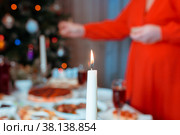 Свечи на праздничном столе и рука, зажигающая свечи на заднем плане. Стоковое фото, фотограф Елизавета Федотова / Фотобанк Лори