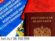 Книжка с Федеральными законами о военной службе, паспорт РФ и военный билет лежат на столе (2022 год). Редакционное фото, фотограф Николай Винокуров / Фотобанк Лори