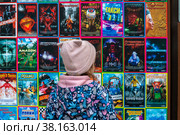 Девочка смотрит афишу 5d кинотеатра в парке города Москвы, Россия (2022 год). Редакционное фото, фотограф Николай Винокуров / Фотобанк Лори