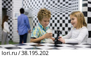 Boy adn girl solving puzzle together in room stylized like chessboard. Стоковое фото, фотограф Яков Филимонов / Фотобанк Лори