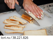 Сhef cuts crusts off bread for salad. Process of preparing delicious salad "Caesar". Concept of culinary skills and catering. Copy space. Стоковое фото, фотограф Aleksandr Golubev / Фотобанк Лори