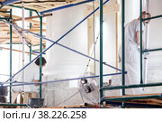 Workers restore white walls on scaffolding in large room. Construction works, interior repairs, restoration and reconstruction of antique buildings are underway. Стоковое фото, фотограф Aleksandr Golubev / Фотобанк Лори