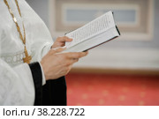 Priest holds book of prayers for baptism in Church. Ritual of Orthodox sacrament of baptism. Reading prayer in Orthodox rite. Bible. Стоковое фото, фотограф Aleksandr Golubev / Фотобанк Лори