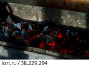 Hot coals. Coal combustion. Close-up of red-hot coals blazing on grill. Close up. View from top. Dark background for creative process. Barbecue process. Home cooking. Стоковое фото, фотограф Aleksandr Golubev / Фотобанк Лори