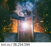 Working man welder burns through an electrode hole in a steel channel in the evening, the view from the top. Стоковое фото, фотограф Андрей С / Фотобанк Лори