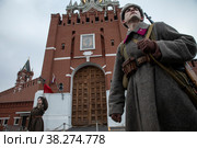Молодой человек в форме советского солдата Великой Отечественной войны стоит на фоне Спасской башни Московского кремля на Красной площади в городе Москве, Россия (2022 год). Редакционное фото, фотограф Николай Винокуров / Фотобанк Лори