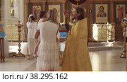 RUSSIA, KAZAN 08-28-2022: baptism in the Orthodox Church - a woman photographs a mother with a baby and a priest. Редакционное видео, видеограф Константин Шишкин / Фотобанк Лори
