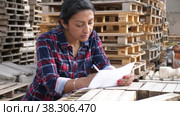 Female worker with tablet checking quantity of paving slabs in warehouse of building materials. Стоковое видео, видеограф Яков Филимонов / Фотобанк Лори