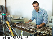 Farmer man working with automatic filling and seeding line for growing containerized seedlings of decorative plants in greenhouse. Стоковое фото, фотограф Яков Филимонов / Фотобанк Лори