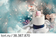 Cozy Christmas still life. concept of warmth and comfort during the cold winter holidays. cup of coffee or hot chocolate with marshmallows on the Christmas table. glare of the garland adds a festive atmosphere. Стоковое фото, фотограф Оксана Медведева / Фотобанк Лори