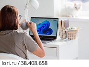 A young happy beautiful business woman freelancer, sitting in a home office with a laptop, smartphone and drinking coffee. A woman works at home. The cat is in the background. Стоковое фото, фотограф Photojuli / Фотобанк Лори