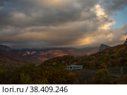 Beautiful clouds in the evening sky over a mountain valley and a wooden house on a hill. Стоковое фото, фотограф Яна Королёва / Фотобанк Лори