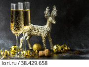 С Новым 2023 годом. Фон рождественских и новогодних праздников с пространством для копирования. Два бокала и золотой блестящий олень на темном фоне. Стоковое фото, фотограф Photojuli / Фотобанк Лори