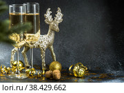 С Новым 2023 годом. Фон рождественских и новогодних праздников с пространством для копирования. Два бокала и золотой блестящий олень на темном фоне. Стоковое фото, фотограф Photojuli / Фотобанк Лори