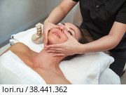 Facial massage woman in SPA salon. Massaging therapist makes face therapy massage for female. Sensual healthy massaging in hands of professional masseur. Concept of health care and beauty. Copy space. Стоковое фото, фотограф Aleksandr Golubev / Фотобанк Лори