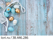 Золотые, голубые, белые яйца в авоське на синем деревянном фоне. Геометрия. Минимальная концепция. Вид сверху. Пасхальная открытка с копией места для текста. Праздник Светлая пасха. Стоковое фото, фотограф Photojuli / Фотобанк Лори